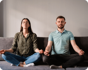 couple meditating in a cross-legged position on a couch