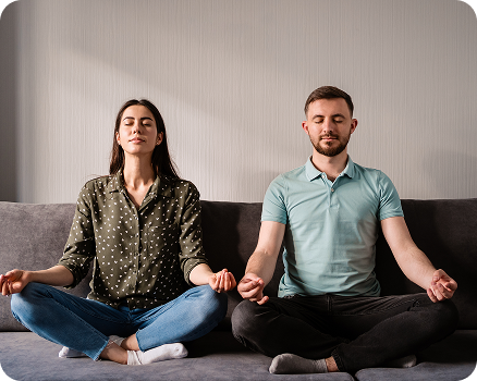 couple meditating in a cross-legged position on a couch